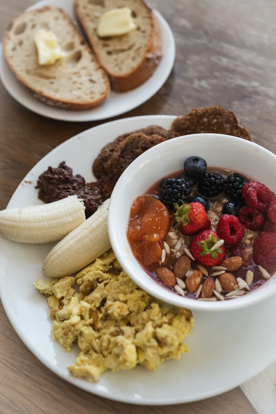 Déjeuner : bol de fruits rouges et noix, œufs brouillés, banane et pain grillé